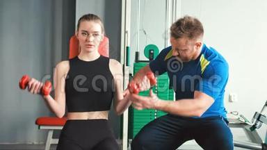 美女在健身房的私人教练的帮助下做举重运动